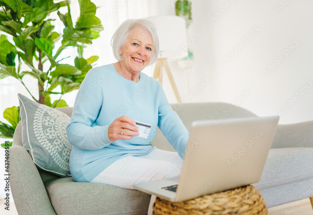 portrait of elderly woman sit on the sofa at home with computer buy on the internet portrait of elderly woman sit on the sofa at home with computer buy on the internet