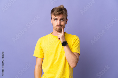 Young handsome blonde man isolated on purple background and thinking