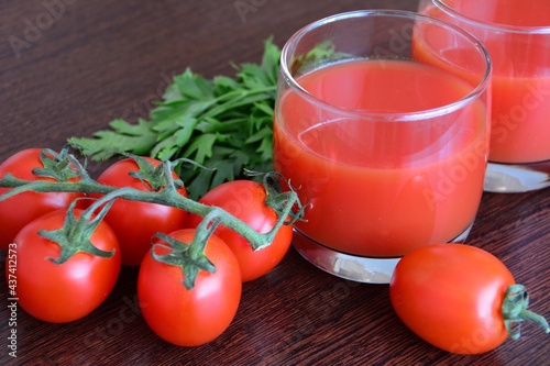 tomato juice in glass with tomatoes, parsley, salad geens on the wooden background