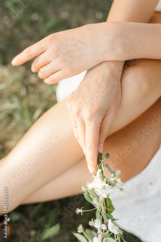 Fototapeta Naklejka Na Ścianę i Meble -  women's hands hold an apple tree branch. Street and green grass, sunny day. The concept of spring flowering.