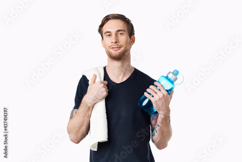 man in black t-shirt with bottle of water in hand and towel on shoulder cropped view