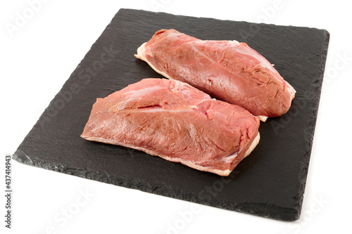 Two raw duck breast fillets on black slate plate, isolated on white