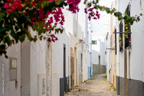 Fototapeta Naklejka Na Ścianę i Meble -  Narrow street with white houses and flowers in Olhao, south of Portugal