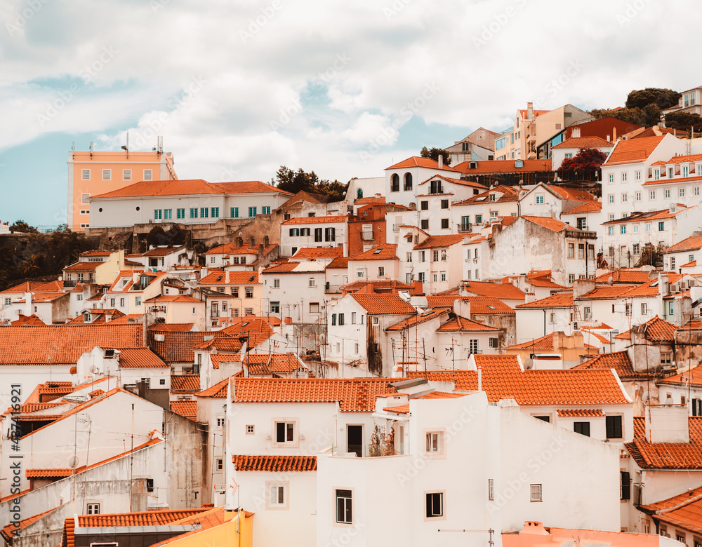 Plenty of traditional crowded antique residential houses with orange clay triangle roofs on the hill of Lisbon, Portugal on a warm sunny day