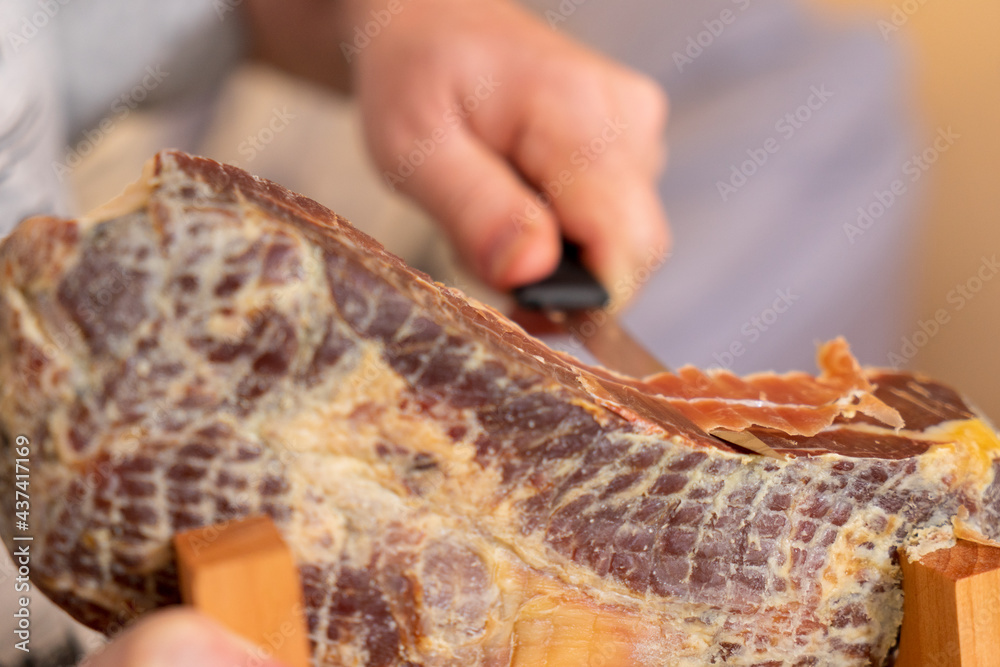 Man cuts mini ham with a special knife.