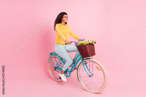 Fototapeta Naklejka Na Ścianę i Meble -  Portrait of attractive cheerful girl riding bike spending free time isolated over pastel pink color background