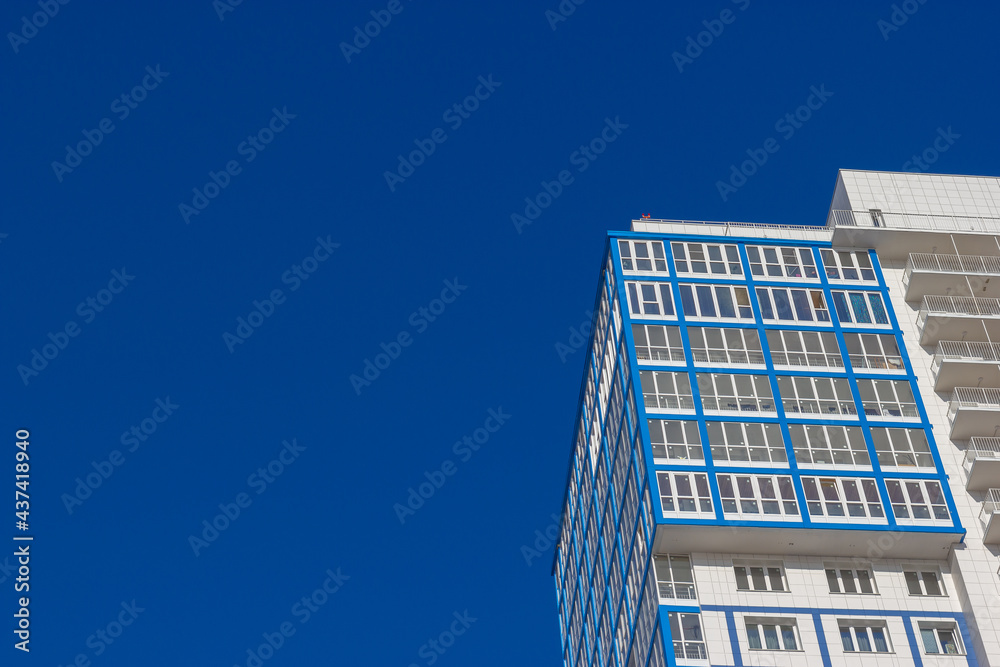 Bottom view of the facade of a high residential building against a blue sky Bottom view of the facade of a high residential building against a blue sky