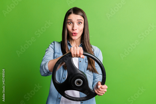 Portrait of attractive cheerful girl holding steering wheel pretending drive pout lips isolated over bright green color background