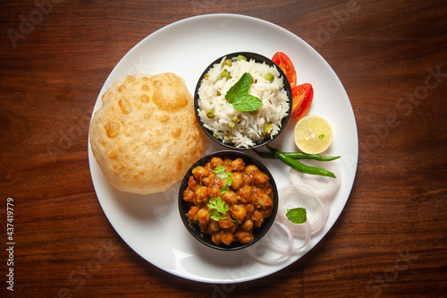 Chickpeas masala (Spicy chola or chhole curry) and Bhatura or Puri garnished with fresh green coriander and ingredients. A Classic Indian typical Panjabi street food. photo