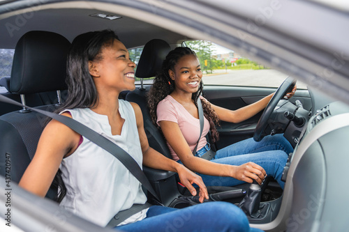 Young black teenage driver seated in her new car with her mother © Louis-Photo