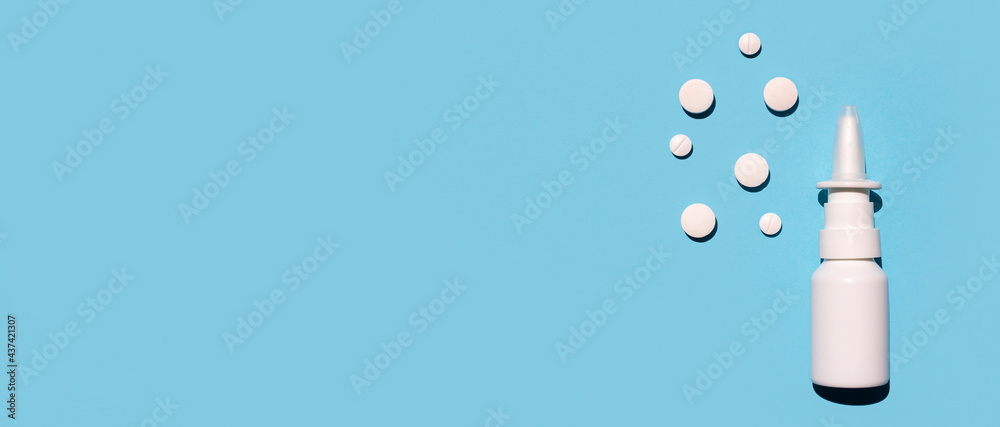 Nasal spray and pills on a blue background. Treating seasonal allergies. Top view, space for text.
