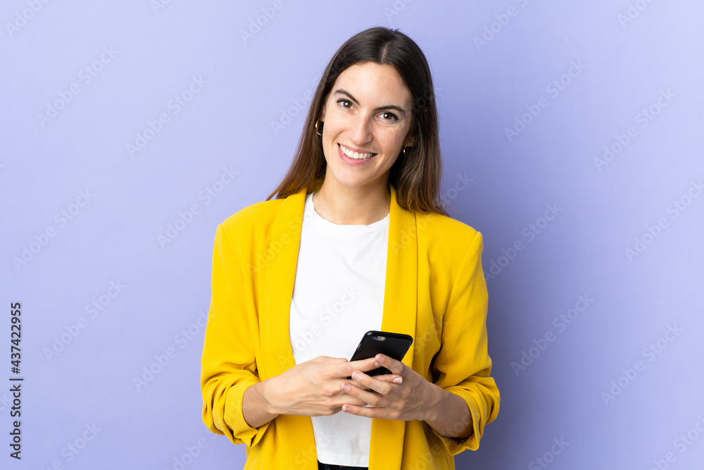 Young caucasian woman over isolated background sending a message with the mobile Young caucasian woman over isolated background sending a message with the mobile