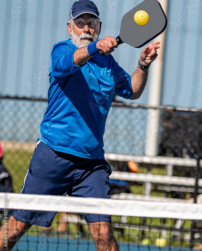 Senior man hits a hard volley in the game of pickleball photo