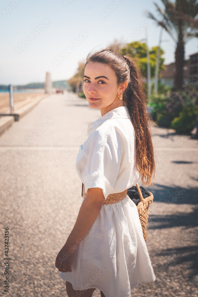 Beautiful girl with a white dress walking thorugh a coast village