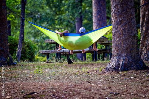 Young couple relax in a bright yellow hammock on a summer day in the forest photo