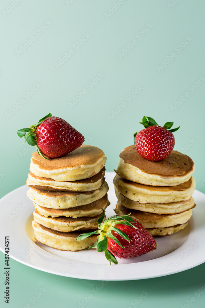 Stack of Fluffy and Small Homemade Pancakes with Fresh Berries on White Plate Breakfast Green Background Vertical