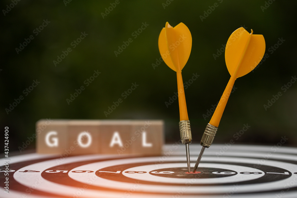 Fototapeta premium Yellow dart arrows hitting in the target center of dartboard with modern people and text 