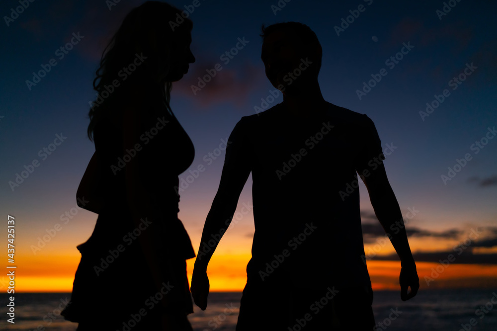 Unrecognizable couple walking near sea in evening