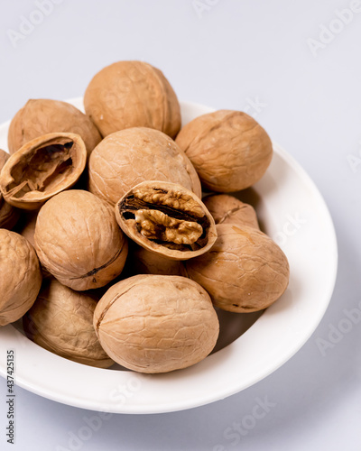 Walnuts in a White Plate on Blue Background Nuts Close Up Vertical