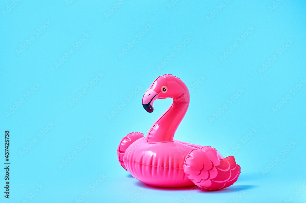 Inflatable pink flamingo pool toy on blue background. Creative minimal concept - obrazy, fototapety, plakaty 