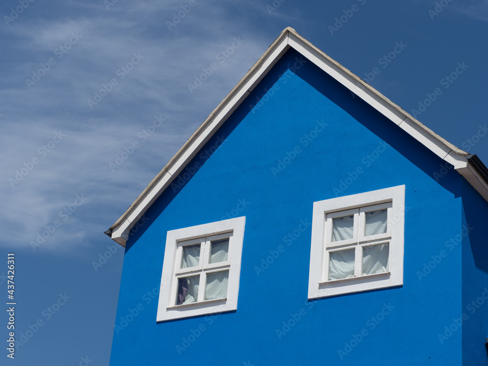 A striking blue walled building with white windows against a blue sky.Contrasting colour in architecture