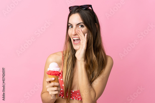Young caucasian woman holding an ice cream isolated on pink background shouting with mouth wide open