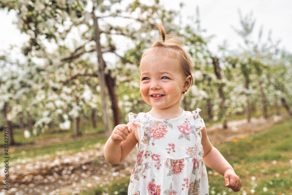 Adorable little smiling baby girl playing in a blooming apple garden Adorable little smiling baby girl playing in a blooming apple garden
