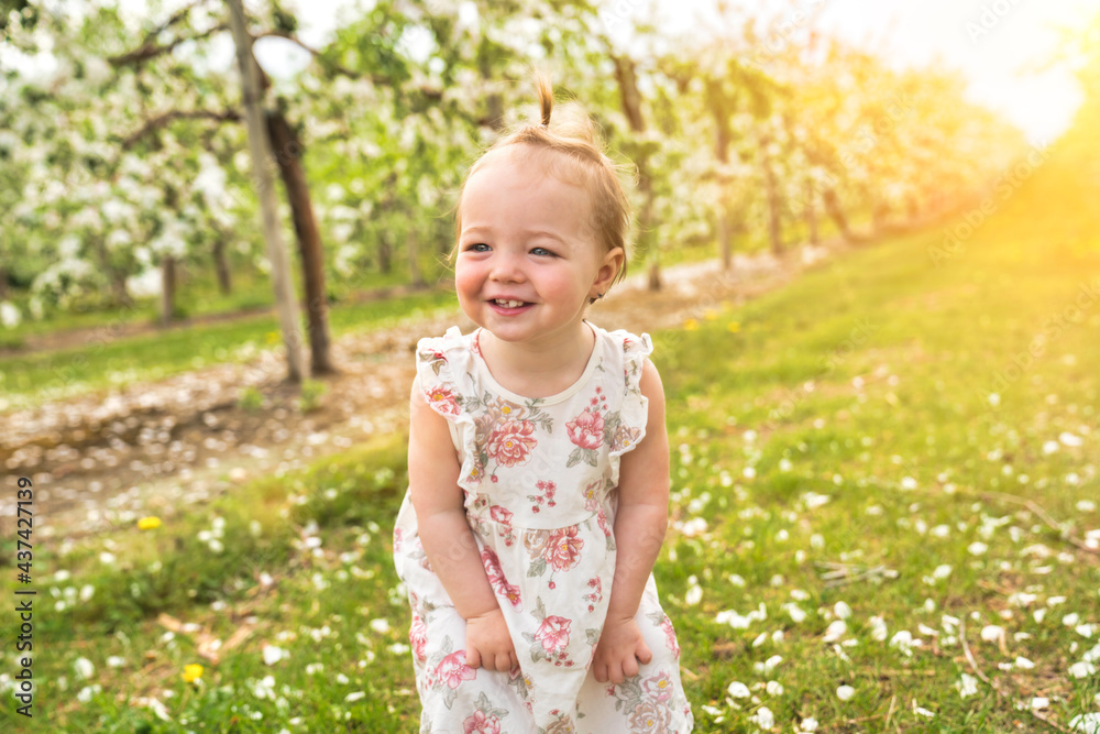 Adorable little smiling baby girl playing in a blooming apple garden Adorable little smiling baby girl playing in a blooming apple garden