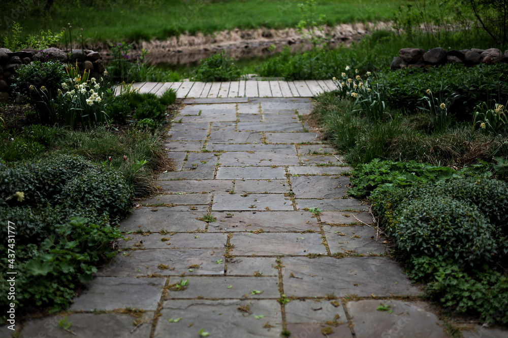 Stone Path in Garden with Green Bushes and a River