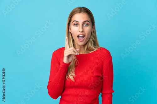 Young blonde woman isolated on blue background intending to realizes the solution while lifting a finger up