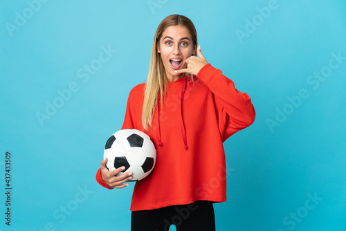 Young football player woman isolated on blue background making phone gesture. Call me back sign