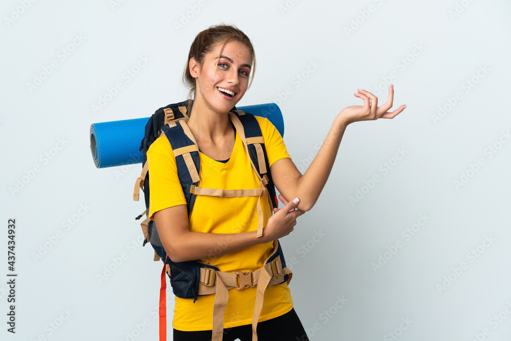 Young mountaineer woman with a big backpack isolated on white background extending hands to the side for inviting to come