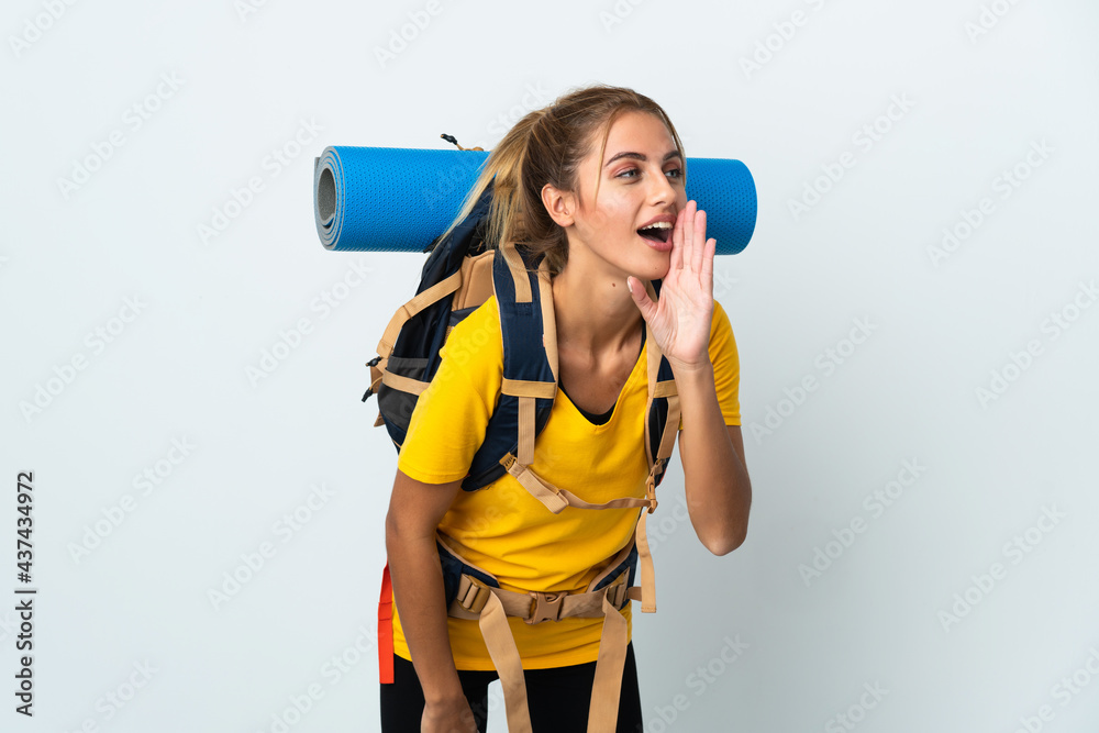 Young mountaineer woman with a big backpack isolated on white background shouting with mouth wide open to the side Young mountaineer woman with a big backpack isolated on white background shouting with mouth wide open to the side