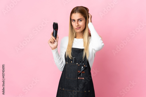 Young hairdresser woman isolated on pink background having doubts