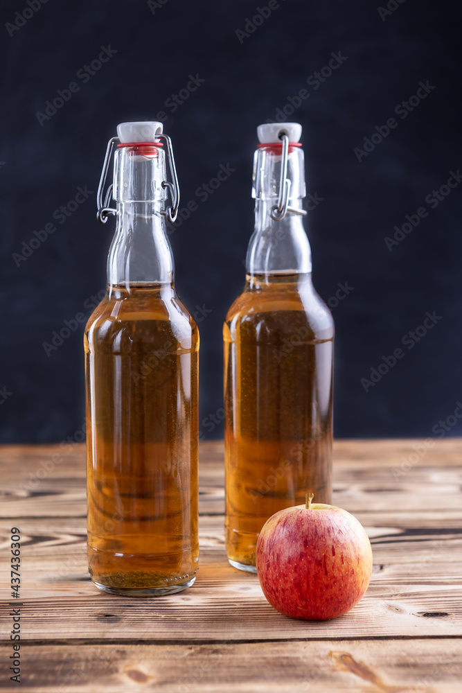 homemade apple cider in bottles and an apple on a wooden background. selective focus homemade apple cider in bottles and an apple on a wooden background. selective focus