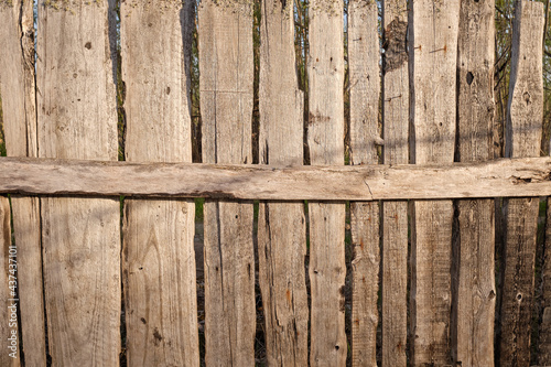 Old wooden fence against sky with clouds. Dilapidated village fence on a cloudy day. Silence and desolation.