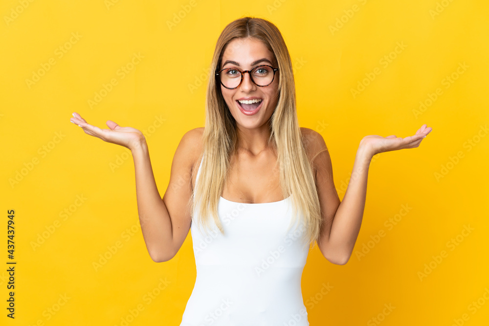 Young blonde woman isolated on yellow background with shocked facial expression Young blonde woman isolated on yellow background with shocked facial expression