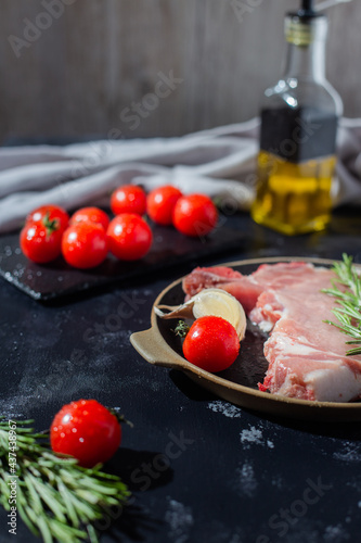 pork steak with cherry tomato and other ingredients such as rosemary, garlic, olive oil. copy space