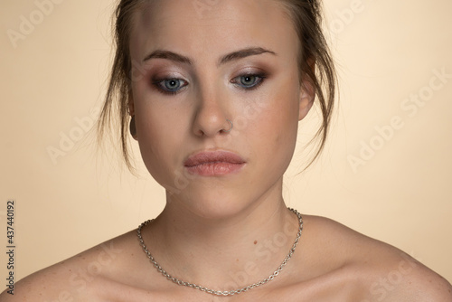 a brooding girl with eyes of different colors looks down , she has an interesting short hairstyle