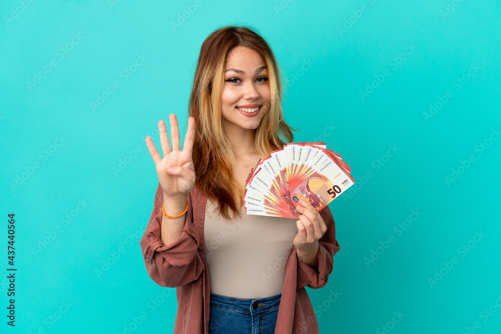 Teenager blonde girl taking a lot of Euros over isolated blue background happy and counting four with fingers Teenager blonde girl taking a lot of Euros over isolated blue background happy and counting four with fingers