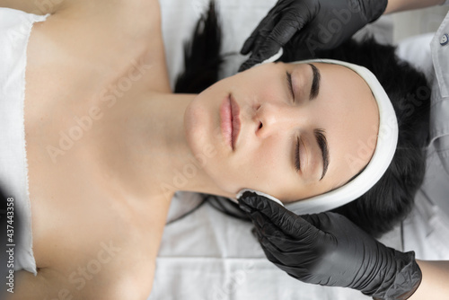 Wipe with sterile napkin face. Young pretty woman receiving treatments in beauty salons.