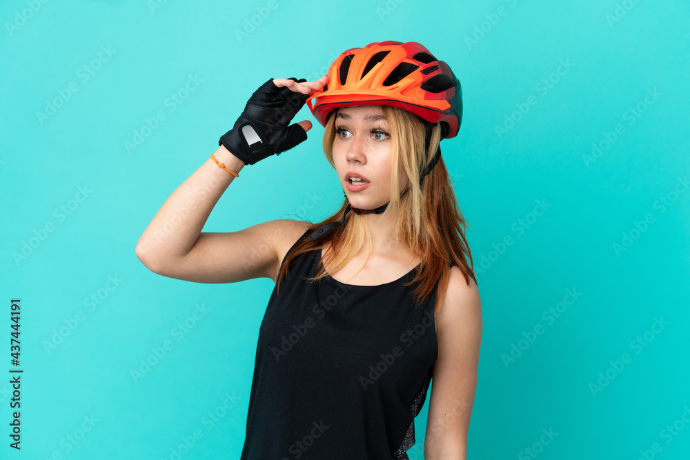 Young cyclist girl over isolated blue background with surprise expression while looking side Young cyclist girl over isolated blue background with surprise expression while looking side