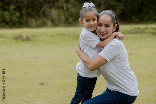 Little girl hugging her mom in the park-young hispanic mom with her daughter outdoors