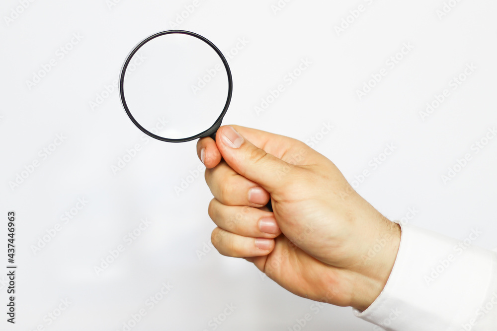 A businessman in a white shirt is holding a magnifying glass. white background. business and finance A businessman in a white shirt is holding a magnifying glass. white background. business and finance