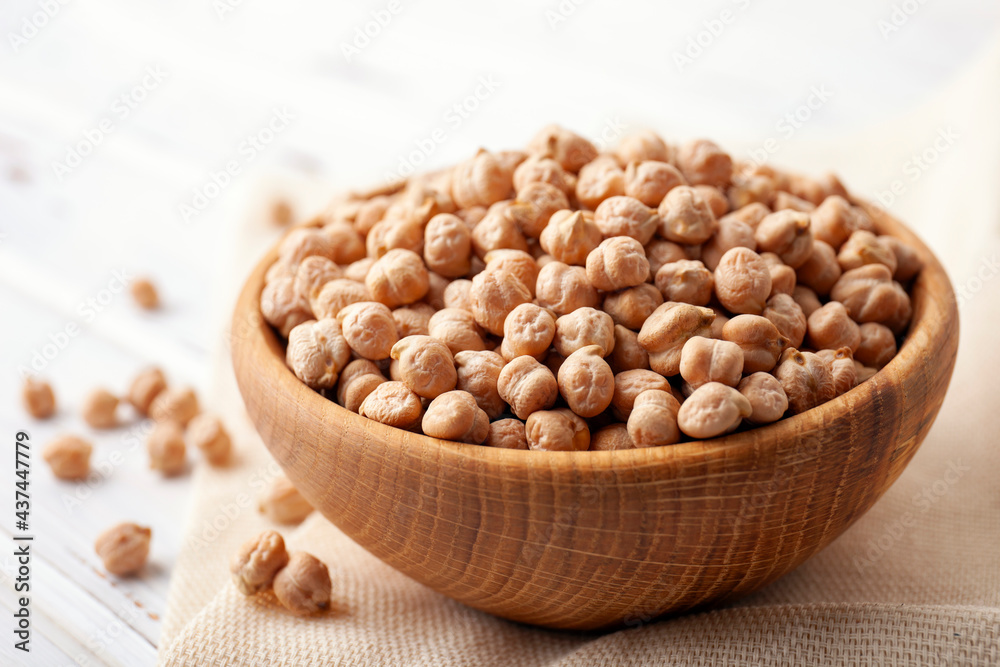 Raw chickpea beans in wooden bowl on kitchen table. Uncooked chickpeas Raw chickpea beans in wooden bowl on kitchen table. Uncooked chickpeas