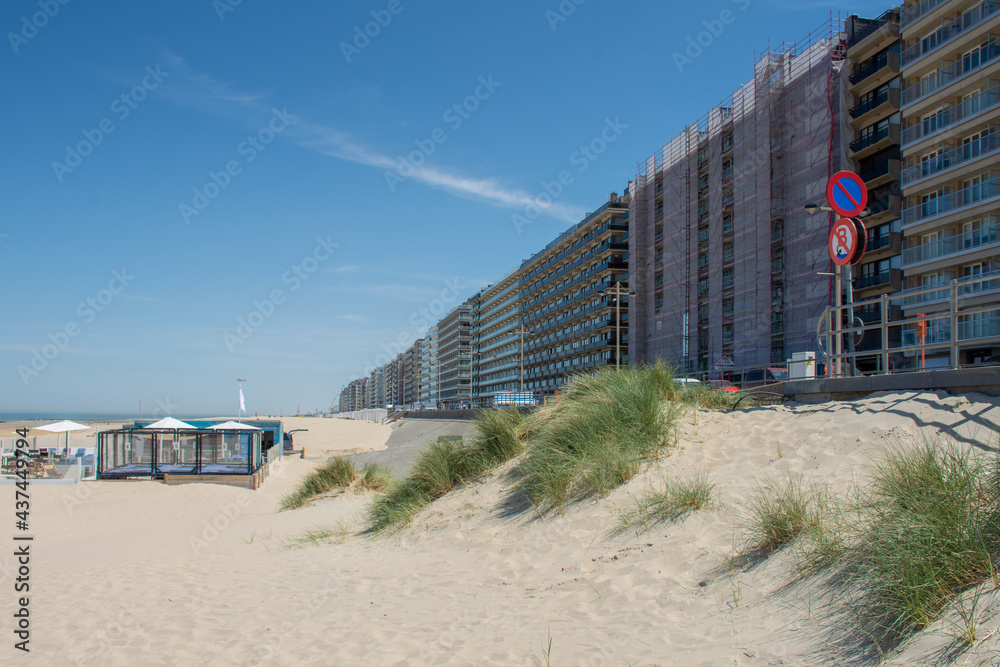 

Apartment buildings on the Belgian coast in Nieuwpoort with some small dunes and beach huts in the foreground