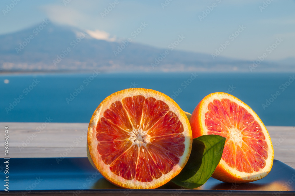 Citrus fruits from Italy: tarocco oranges with blue sea and Mount Etna in the background