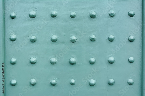 Rivets on a teal painted front door fragment