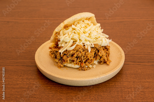 Arepa pelua stuffed to overflowing with shredded meat, cheese strips photo