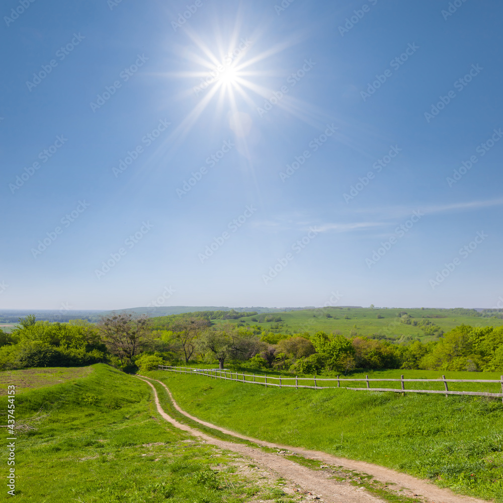 ground road among green hills under a sparkle sun, natural countryside scene